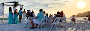 a group of people sitting in chairs on a beach at wedding in Clearwater