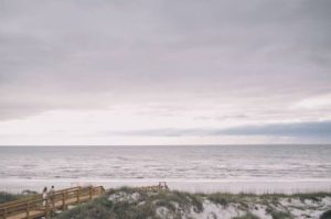 Bride and groom holding hands with Cape San Blas beach in the background